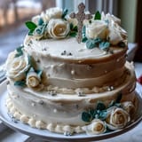 Beautiful vanilla sponge cake with silky buttercream, decorated with delicate white roses and a golden cross topper.