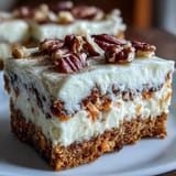 Rich carrot cake and smooth cheesecake swirled together in bars, topped with crunchy nuts for a delightful texture contrast.