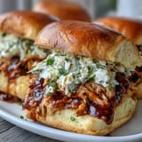 Tender shredded chicken in smoky barbecue sauce, served on toasted buns with coleslaw.  