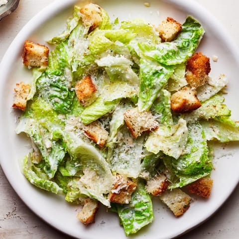 Fresh Caesar salad, featuring crisp romaine lettuce and creamy, homemade dressing, ready to eat.