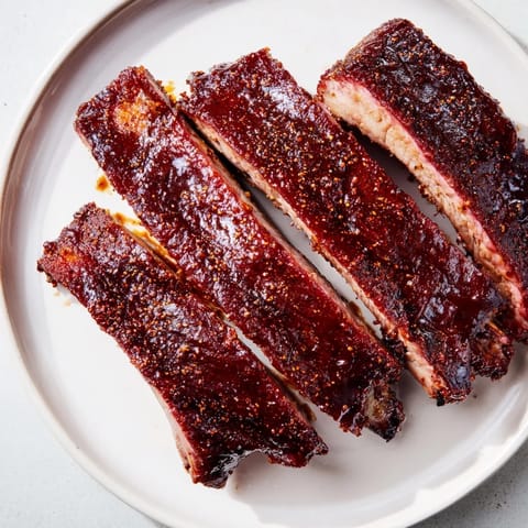 Close-up of fall-off-the-bone BBQ ribs, showcasing the tender meat and rich barbecue sauce.