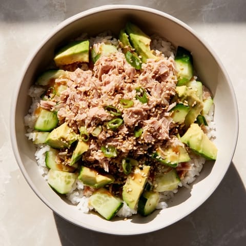 Fragrant jasmine rice topped with tender tuna chunks, diced avocado, crisp cucumber, and scallions, finished with toasted sesame seeds for a nourishing lunch bowl.
