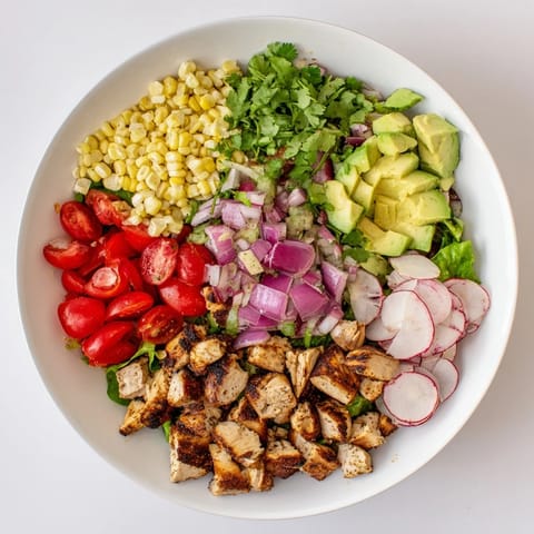 Grilled chicken and charred roasted corn make this chopped salad a hearty, vibrant main dish topped with creamy avocado and crisp radishes.