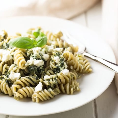 A close-up of Creamy Feta Spinach Pasta, showcasing wilted spinach and melted feta clinging to al dente penne noodles.