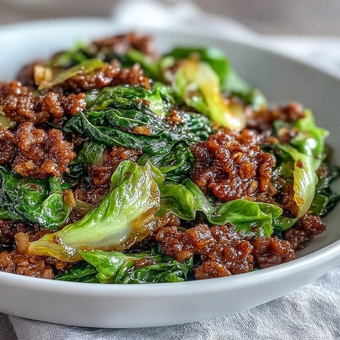 A close-up of Chinese Ground Beef and Cabbage Stir-Fry showcasing saucy ground beef and crisp, tender green cabbage in a wok.