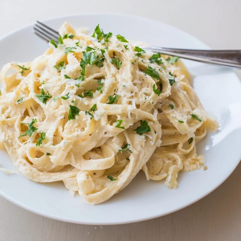 Sriracha Honey Pasta served in a white bowl, paired with a crisp green salad and a glass of chilled white wine.