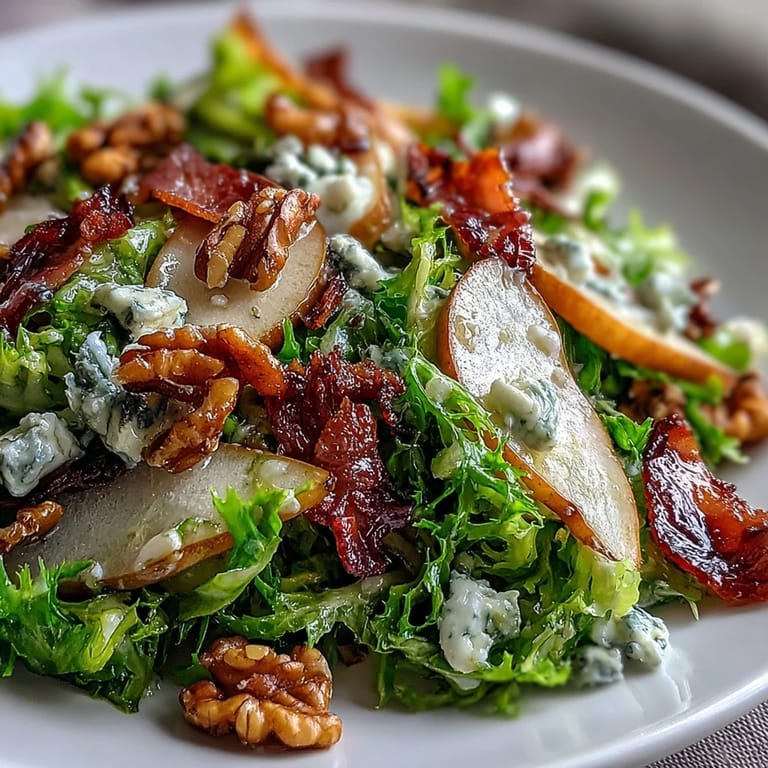 A close-up view of a refreshing Frisée, Pear, Blue Cheese, and Crispy Prosciutto Salad dressed in tangy vinaigrette, featuring a mix of textures from bitter greens and crunchy nuts.