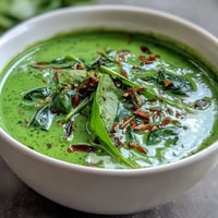 Creamy green Spinach Coriander Lemongrass Soup served hot with lime wedges and cilantro.